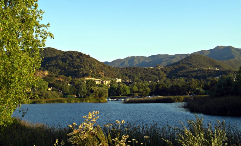 Golden evening light over Lake Sherwood with Santa Monica Mountains and hillside homes beyond