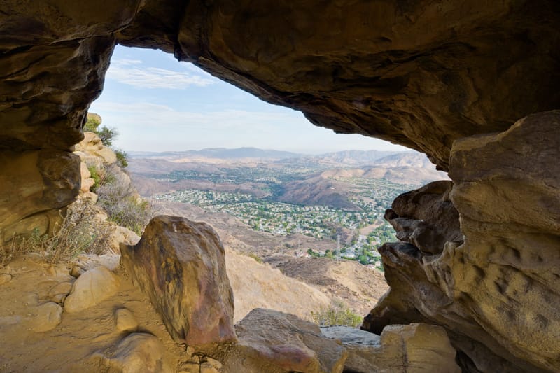 View of Oak Park and the Conejo Valley framed by a sandstone cave arch on Rabbit Ridge Trail