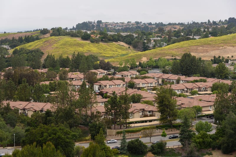 Hillside view of tile roofed homes among rolling green hills in Lang Ranch, Thousand Oaks