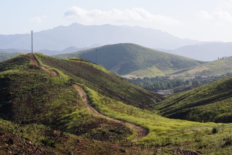 Green rolling hills and dirt trail at Oakbrook Regional Park near Oak Park with Boney Mountain beyond