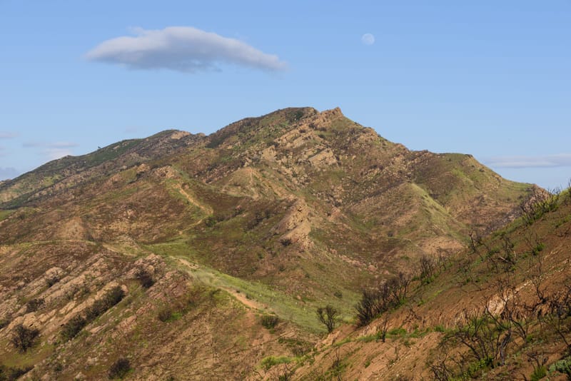 Western summit of Simi Peak rising above Conejo Valley open space near Oak Park at golden hour with moon