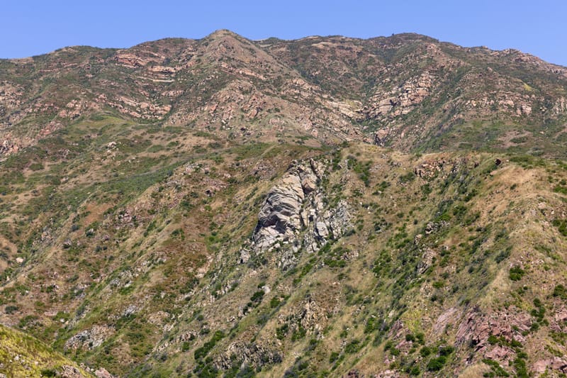 Rugged chaparral ridges and rock outcrops of Malibu Canyon near Calabasas under clear blue sky