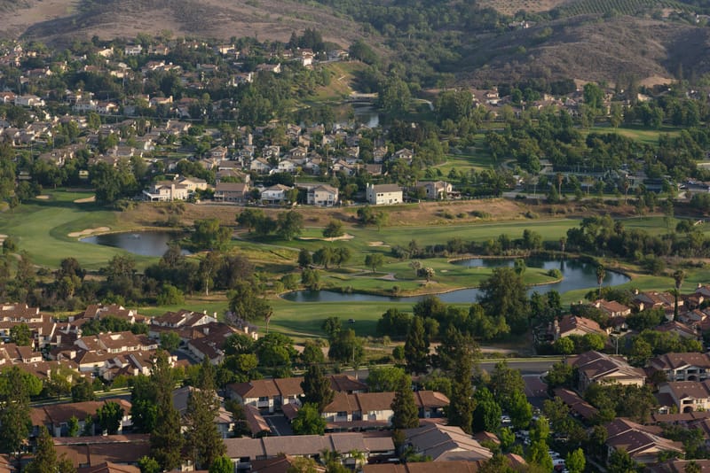 Aerial view of Wood Ranch Golf Club fairways and lakes framed by homes and hills in Simi Valley