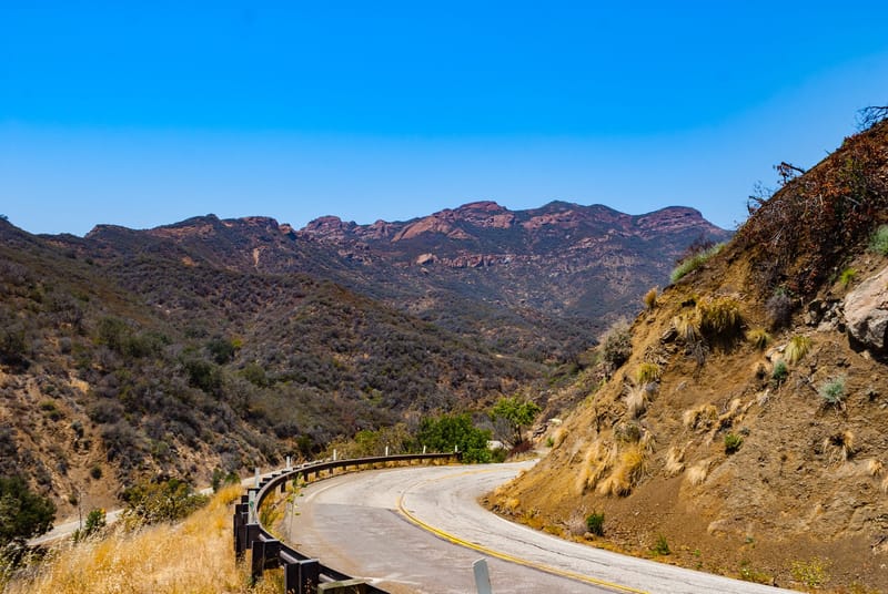 Mulholland Highway curving through the Santa Monica Mountains near Calabasas under a clear blue sky
