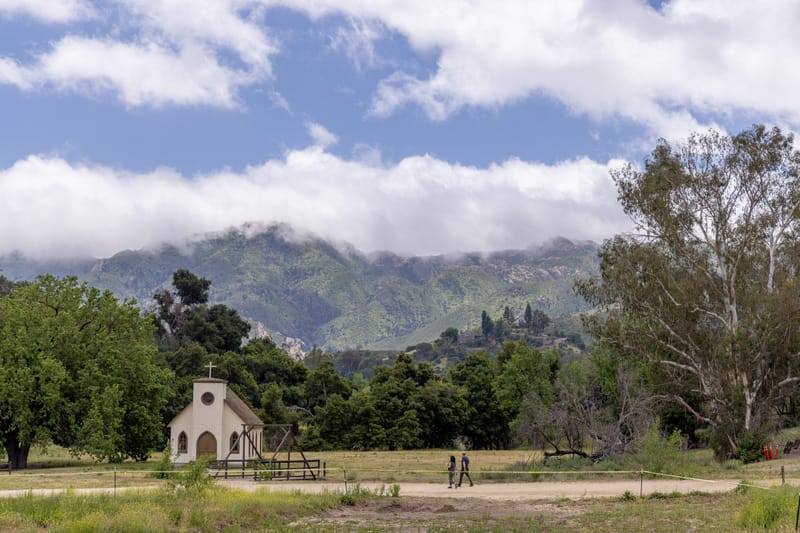 Historic white chapel at Paramount Ranch with cloud draped Santa Monica Mountains beyond