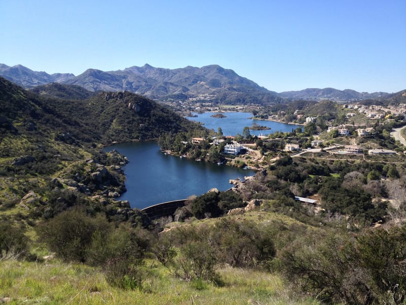 Hillside view of Lake Sherwood, Sherwood Dam and the surrounding hillside homes under a clear blue sky