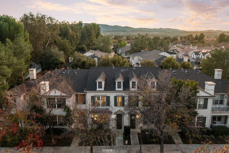 Aerial twilight view of white townhomes with dormer windows and rolling hills beyond