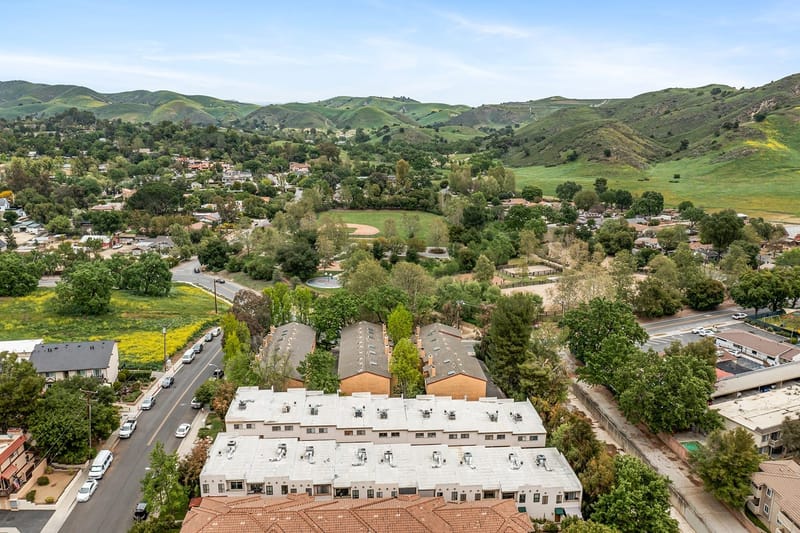 Aerial view of a hillside neighborhood with townhomes, a park ballfield and green rolling hills