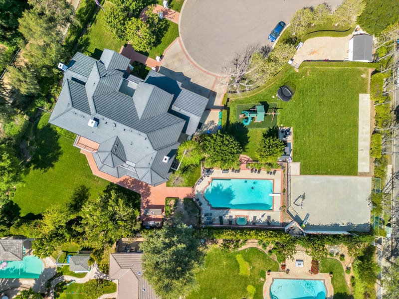 Overhead aerial view of a large estate with pool, sport court, lawn and playground