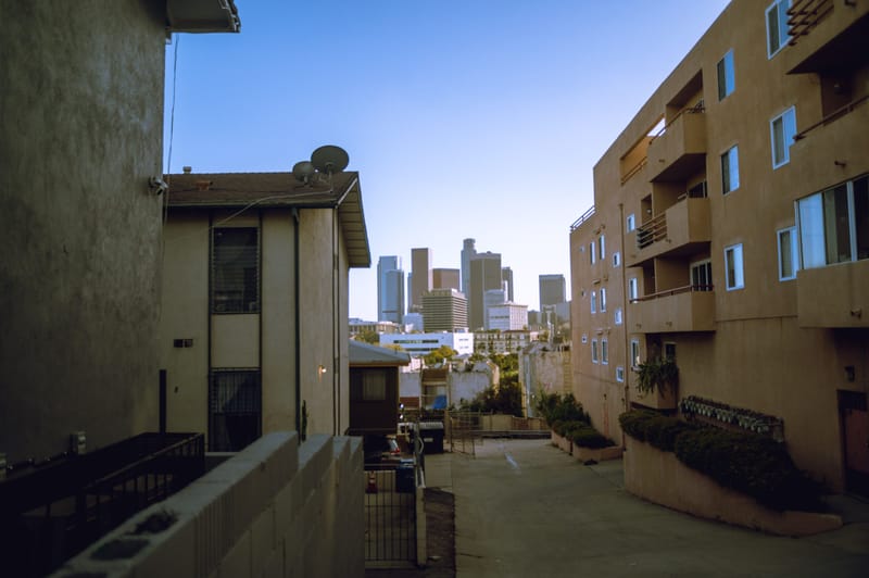 Hillside apartment buildings framing a view of the downtown Los Angeles skyline under clear blue sky.jpg