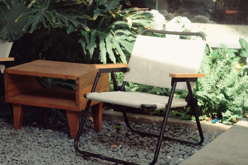 Midcentury folding patio chair and wood side table on gravel beside lush tropical greenery and ferns.in a sunny garden.in.in.in.in.in.in.in.in.in.in.in.in.in.in.in.in.in.in.in.in.in.in.in.in.