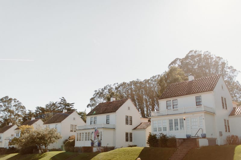 Row of white hillside homes with red tile roofs under hazy California sunlight and eucalyptus trees.pre blank sky.pre plus flag.pre ...a street scene.pre just plain.pre honest view.pre peacef