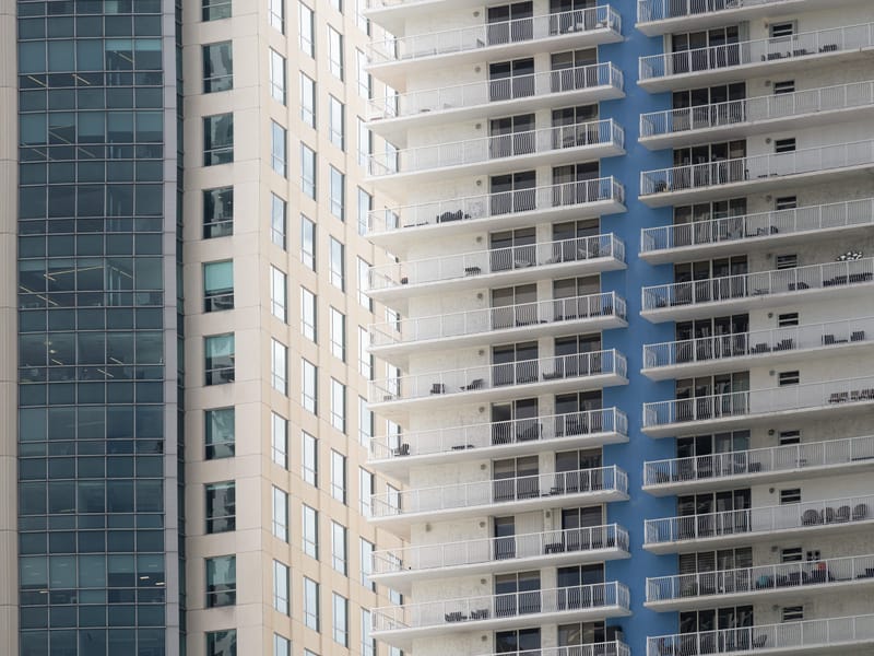 Close view of a high rise condo tower with rows of white balconies beside a glass office building.sixth